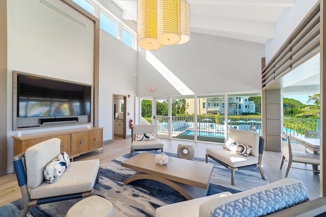 living room featuring light wood-type flooring, high vaulted ceiling, and plenty of natural light