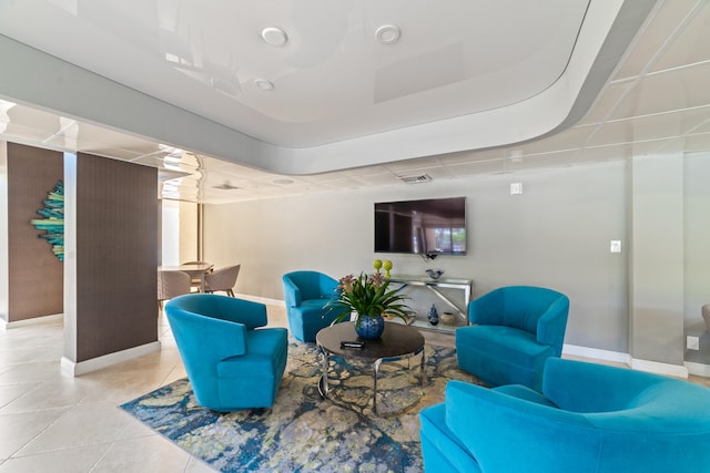 living room with a raised ceiling and light tile patterned flooring