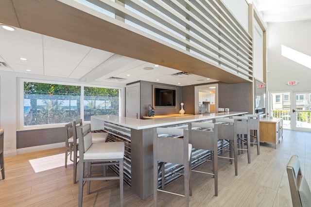 kitchen with a kitchen breakfast bar, kitchen peninsula, light hardwood / wood-style flooring, and a healthy amount of sunlight