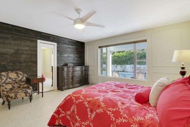 bedroom featuring ceiling fan and wooden walls