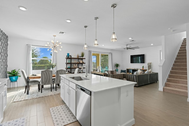 kitchen featuring a center island with sink, dishwasher, hanging light fixtures, ceiling fan with notable chandelier, and white cabinets