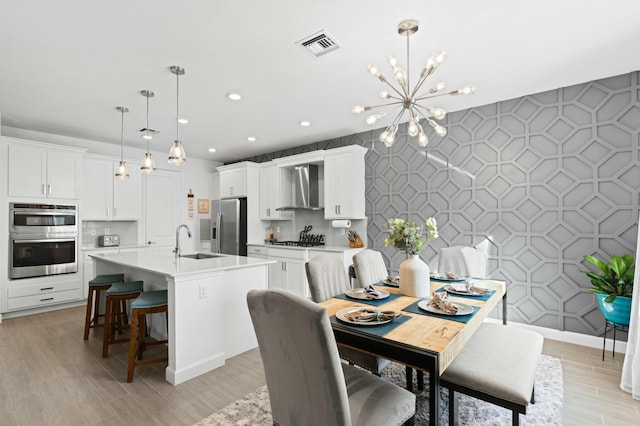 dining area featuring a chandelier, light hardwood / wood-style flooring, and sink