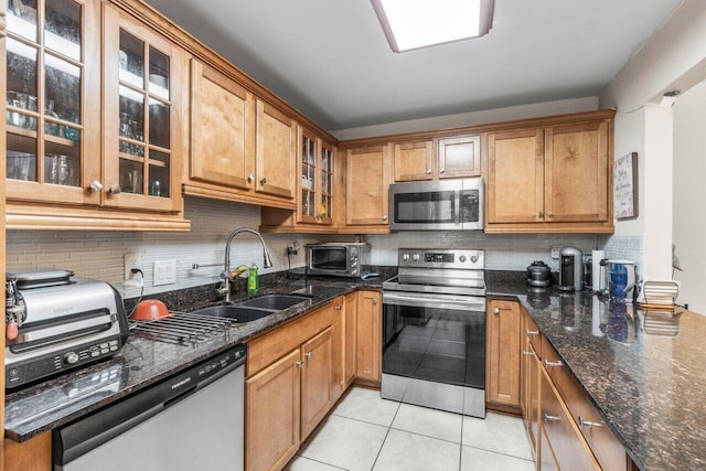 kitchen with decorative backsplash, sink, dark stone counters, and appliances with stainless steel finishes