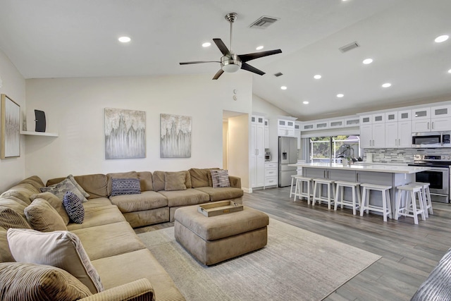 living room with light hardwood / wood-style floors, ceiling fan, and lofted ceiling