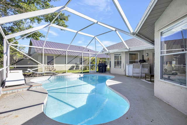 view of swimming pool featuring a patio area, glass enclosure, and grilling area