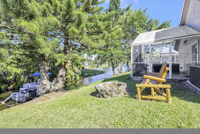 view of yard featuring a fire pit, glass enclosure, and a water view