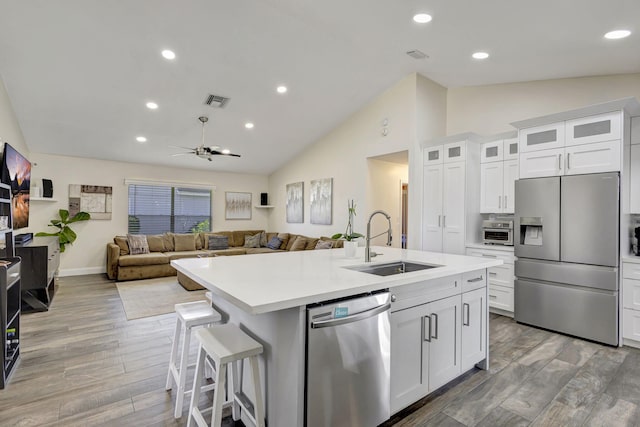 kitchen featuring a kitchen bar, stainless steel appliances, a kitchen island with sink, sink, and white cabinets