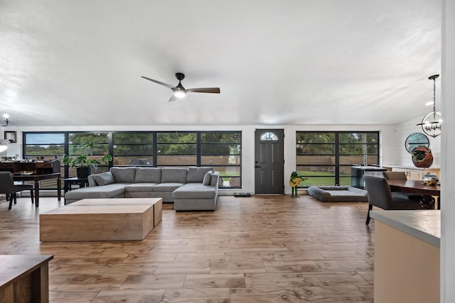 living room featuring a healthy amount of sunlight, ceiling fan with notable chandelier, and light wood-type flooring