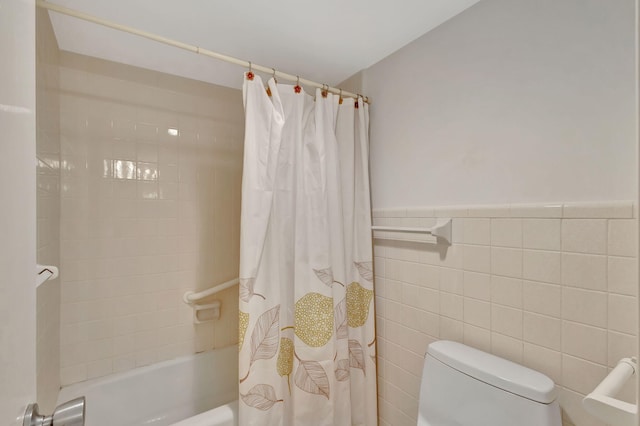 bathroom featuring tile walls, shower / bath combo, and toilet