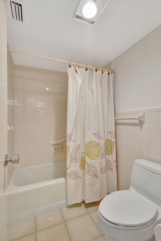 bathroom with tile patterned flooring, shower / bath combination with curtain, toilet, and tile walls