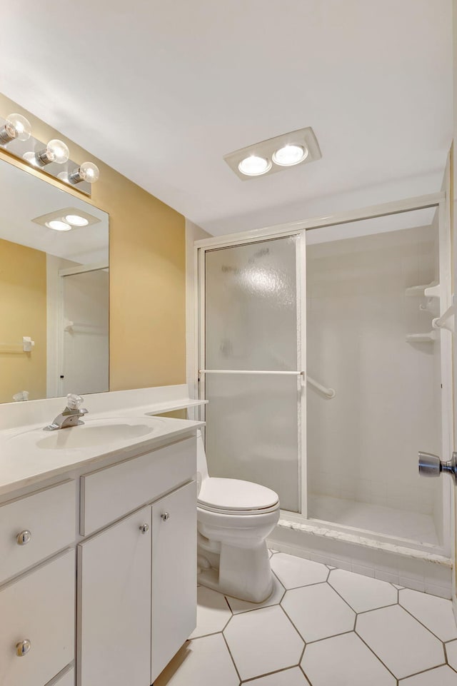 bathroom with tile patterned floors, vanity, toilet, and a shower with door