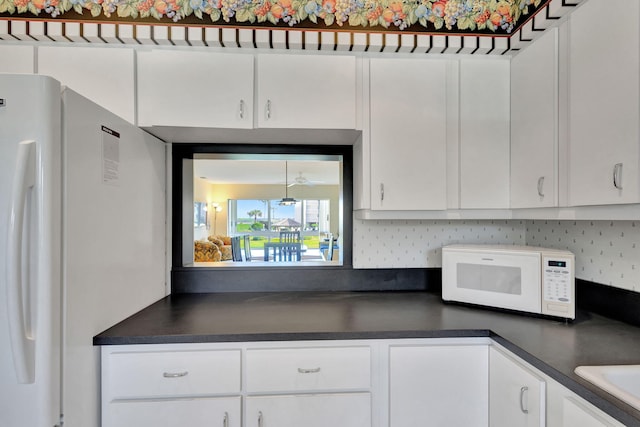 kitchen featuring backsplash, white cabinets, and white appliances