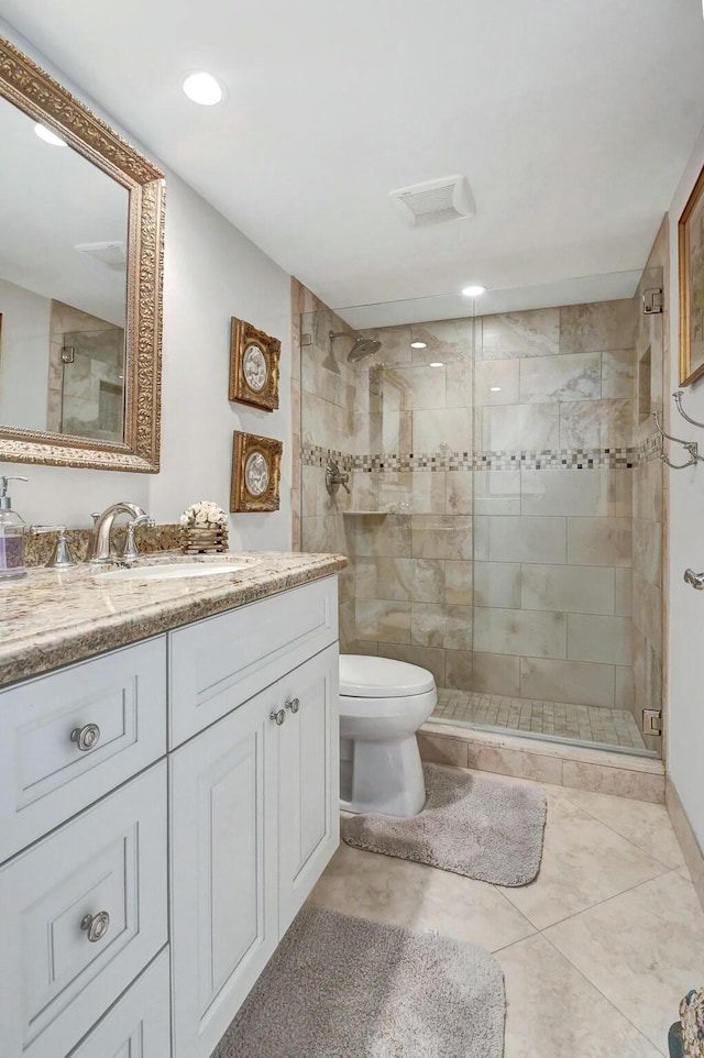 bathroom featuring tile patterned flooring, vanity, a shower with shower door, and toilet