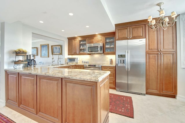 kitchen with sink, light stone counters, kitchen peninsula, decorative backsplash, and appliances with stainless steel finishes