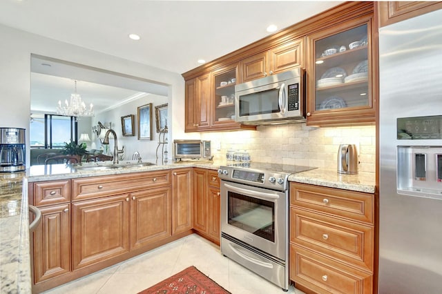 kitchen featuring sink, light stone counters, a chandelier, light tile patterned floors, and appliances with stainless steel finishes