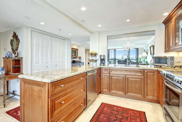 kitchen with sink, light tile patterned floors, appliances with stainless steel finishes, a notable chandelier, and kitchen peninsula