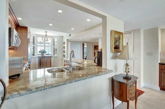 kitchen featuring light tile patterned flooring, light stone countertops, kitchen peninsula, and sink