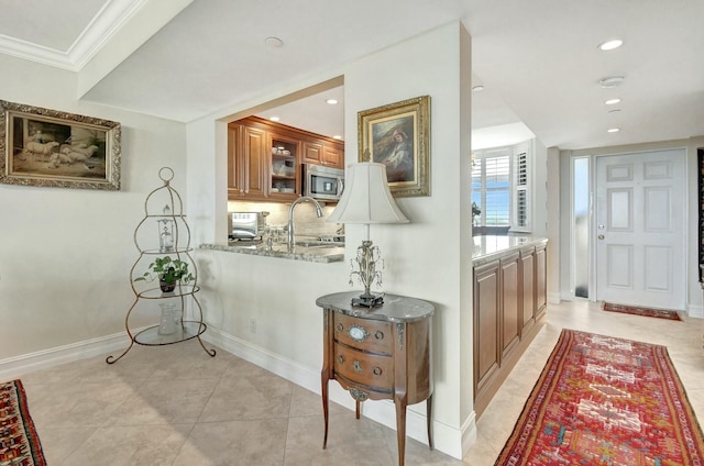 corridor featuring light tile patterned flooring, crown molding, and sink