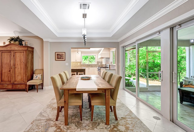 tiled dining room with crown molding and a raised ceiling