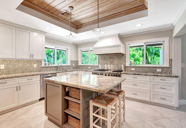 kitchen featuring a tray ceiling, dishwasher, ornamental molding, custom range hood, and a kitchen island