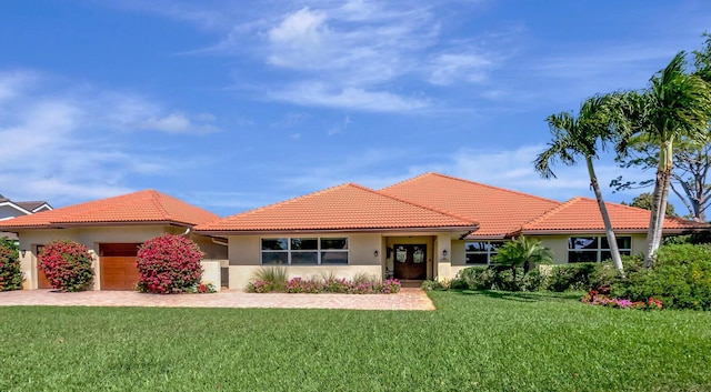 view of front of house with stucco siding, a front yard, a garage, driveway, and a tiled roof