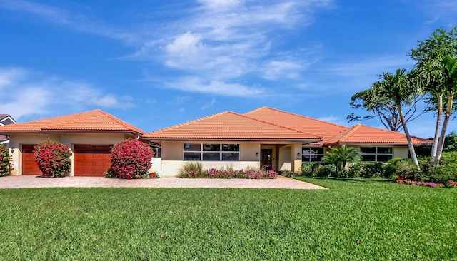 view of front facade featuring a garage, stucco siding, a tiled roof, and a front yard