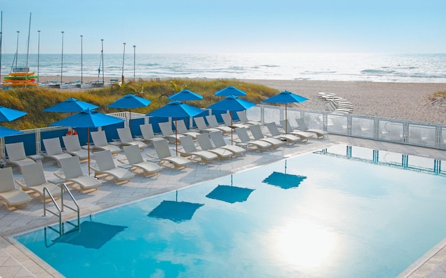 view of pool featuring a water view and a beach view