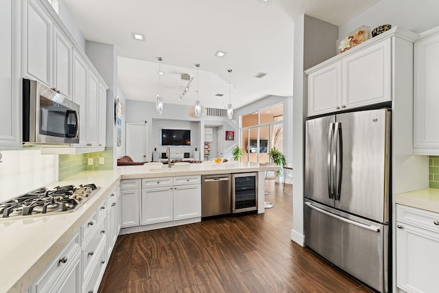 kitchen featuring dark wood-type flooring, kitchen peninsula, tasteful backsplash, white cabinetry, and stainless steel appliances