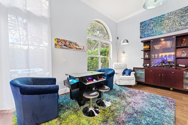 game room with baseboards, vaulted ceiling, crown molding, and wood finish floors