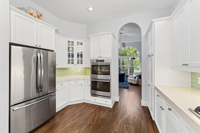 kitchen with tasteful backsplash, dark wood finished floors, stainless steel appliances, and light countertops