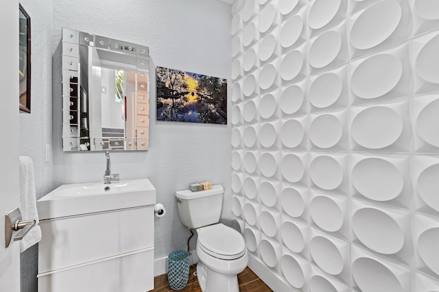 bathroom featuring a textured wall, vanity, toilet, and wood finished floors