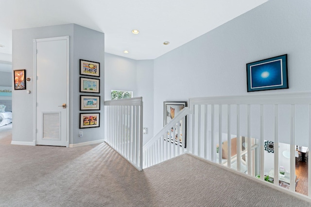 hallway featuring baseboards, visible vents, carpet flooring, an upstairs landing, and recessed lighting