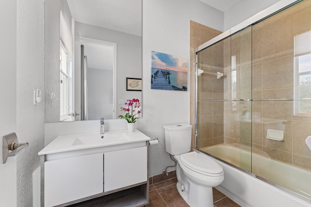 full bathroom with tile patterned floors, vanity, bath / shower combo with glass door, and toilet