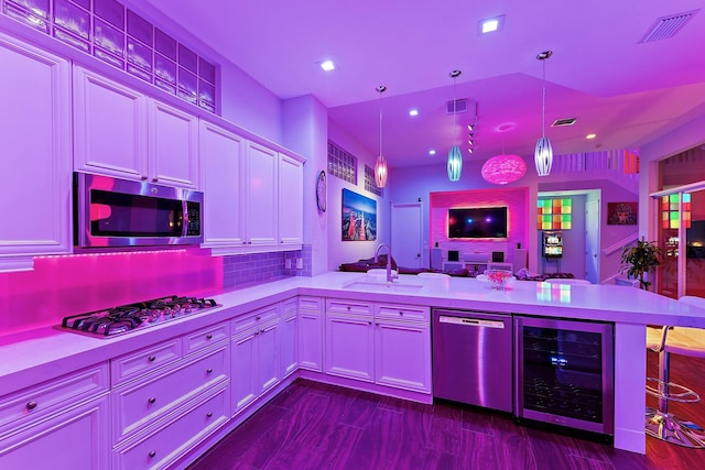 kitchen featuring sink, hanging light fixtures, wine cooler, a kitchen bar, and appliances with stainless steel finishes