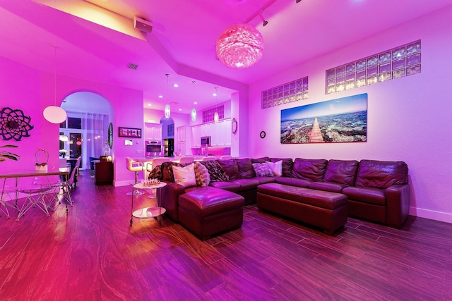 living room featuring visible vents, a notable chandelier, baseboards, and wood finished floors