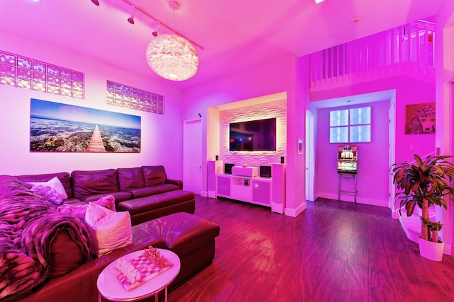 living room featuring baseboards, wood finished floors, rail lighting, and a notable chandelier