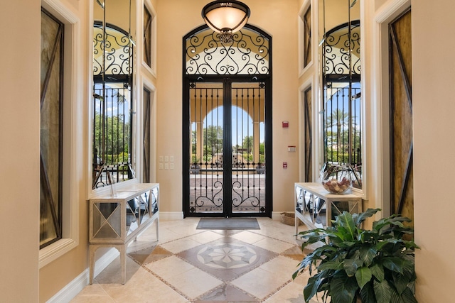 foyer entrance with french doors, baseboards, and tile patterned floors