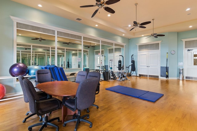 exercise room featuring a raised ceiling, wood finished floors, visible vents, and recessed lighting