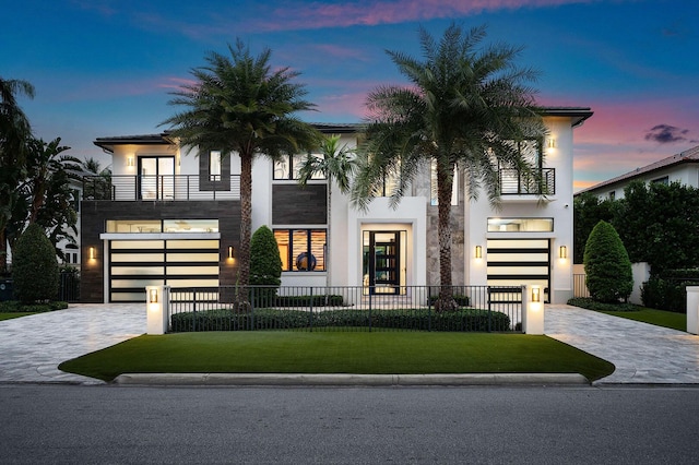 view of front facade featuring a lawn, a balcony, and a garage