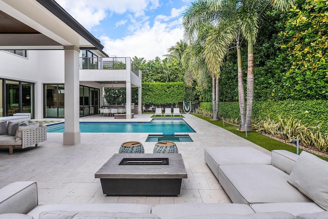 view of swimming pool featuring a patio area, an in ground hot tub, and an outdoor living space with a fire pit