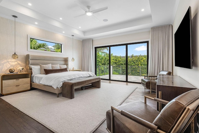 bedroom featuring access to outside, ceiling fan, hardwood / wood-style floors, and a tray ceiling