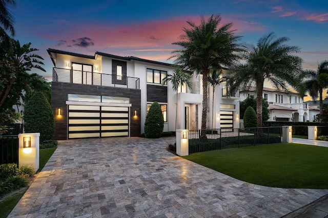 contemporary home featuring a lawn, a balcony, and a garage