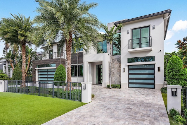 modern home featuring a garage, a balcony, and a front yard