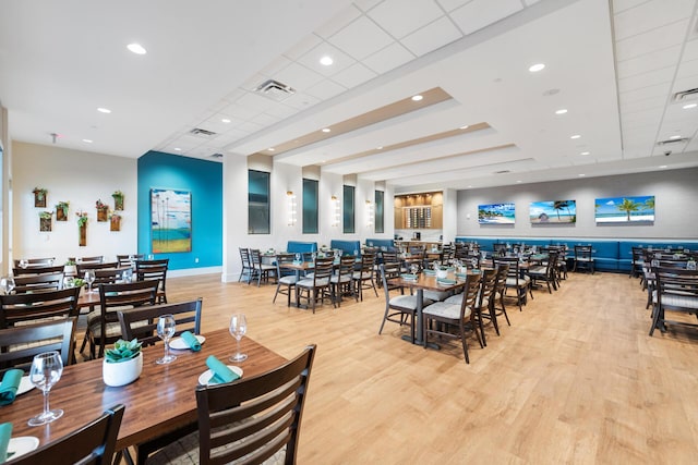 dining space with a drop ceiling and light wood-type flooring