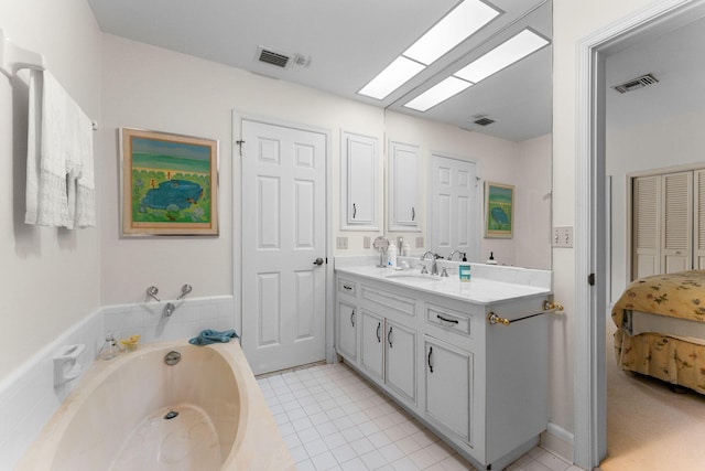 bathroom featuring vanity, a relaxing tiled tub, a skylight, and tile patterned floors