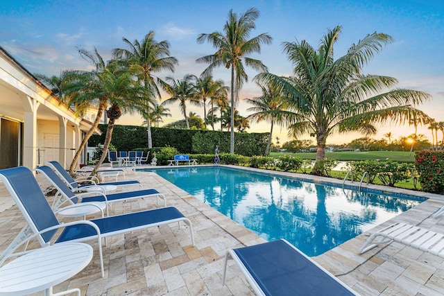 pool at dusk featuring a patio