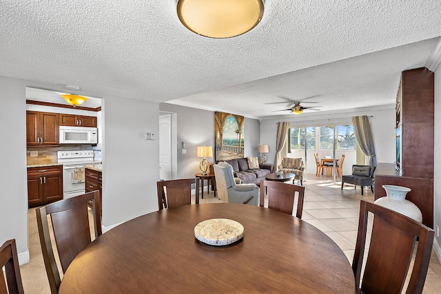 dining space with ceiling fan, light tile patterned floors, a textured ceiling, and ornamental molding