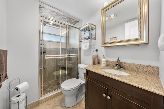 bathroom with a shower with shower door, vanity, toilet, and tile patterned floors