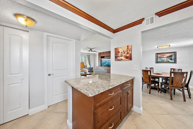 kitchen featuring a textured ceiling, crown molding, light stone counters, and light tile patterned floors