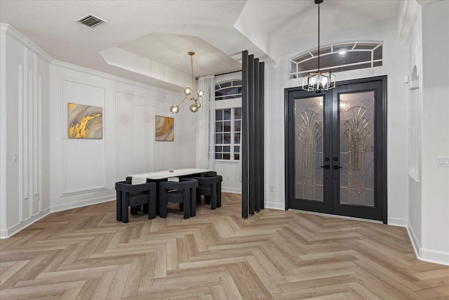 entrance foyer with light parquet flooring, french doors, a textured ceiling, and an inviting chandelier